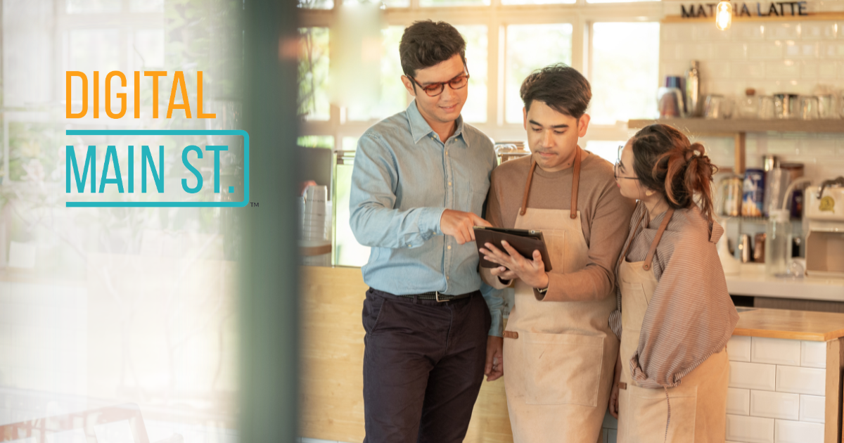 Two men and one woman standing close together looking at a piece of paper