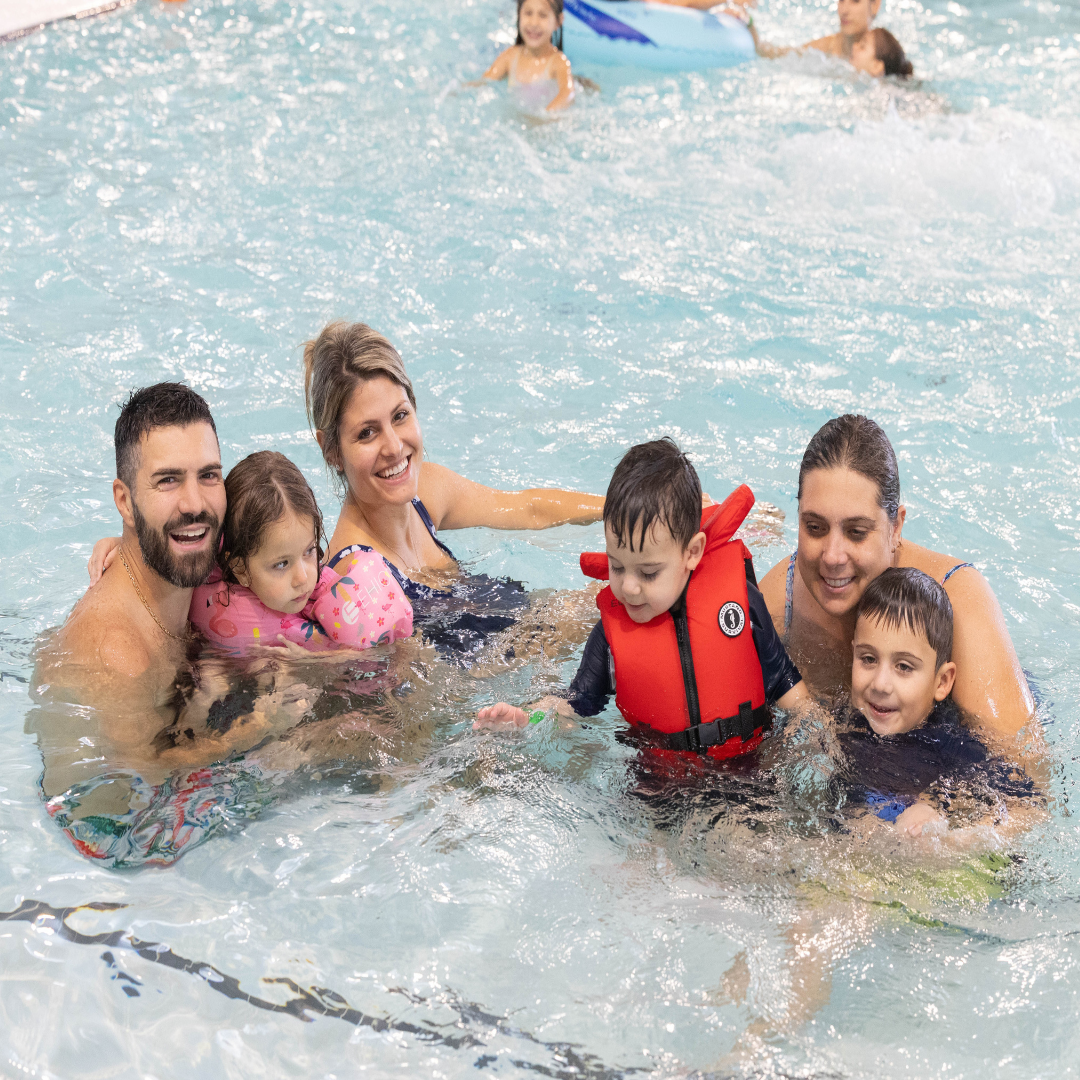 Various people in a pool at the Health and Active Living Plaza smiling into the camera