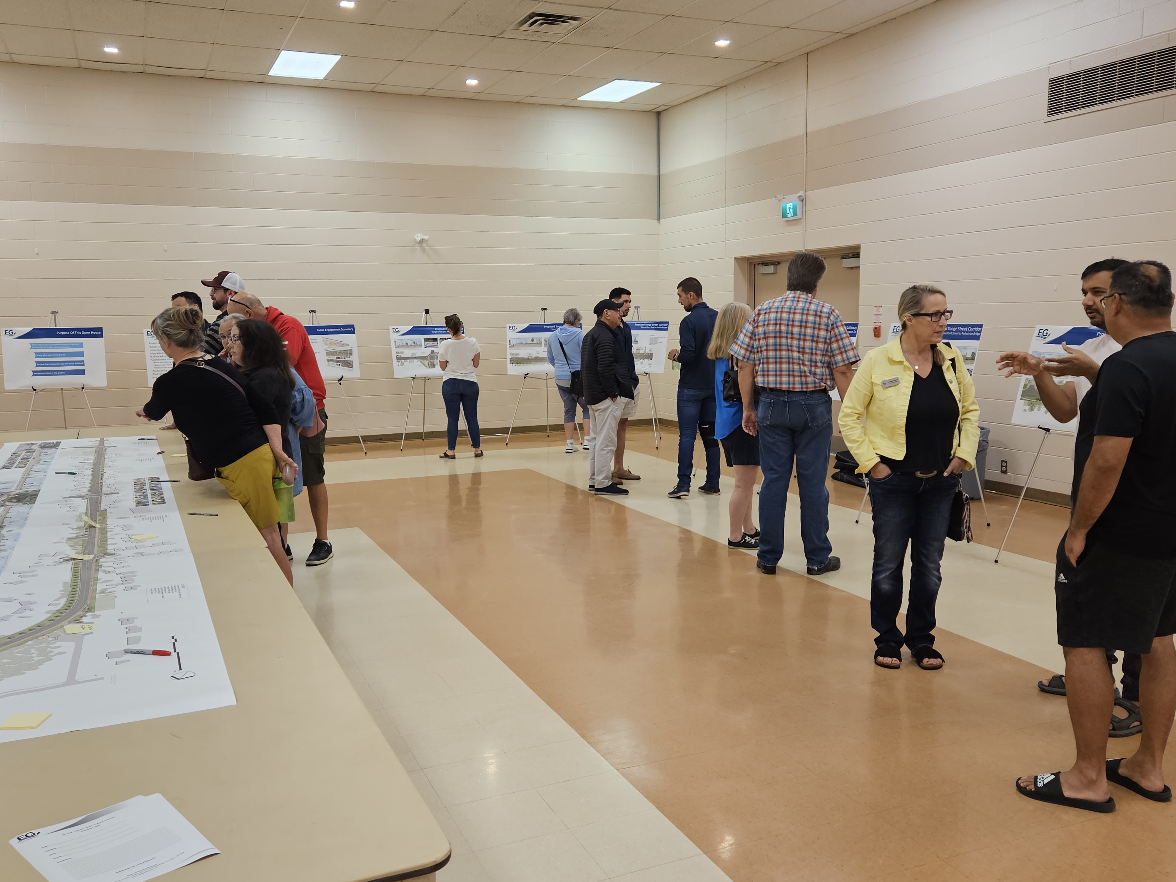 Photo of people standing and discussing the Yonge St. project looking at images on easels