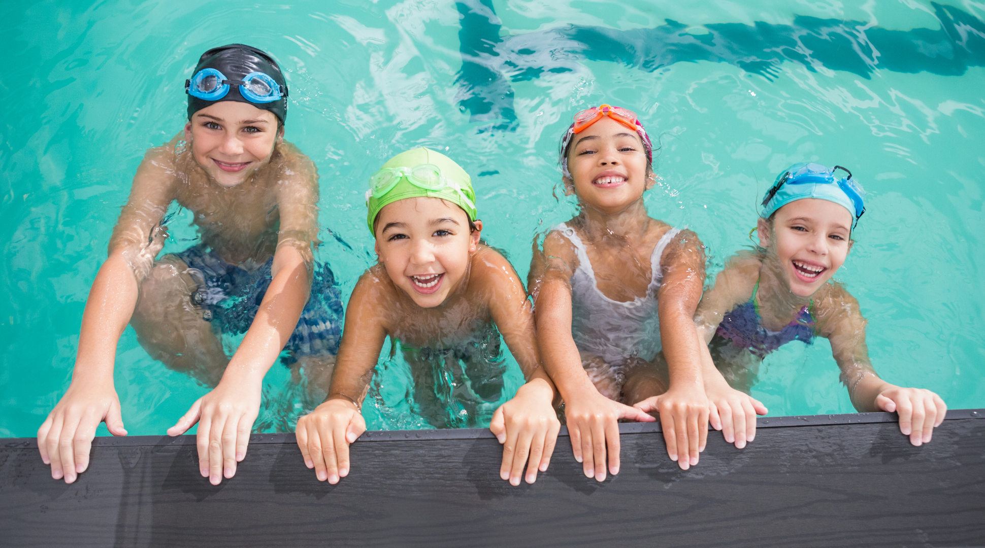 Children hanging onto the edge of a pool smiling