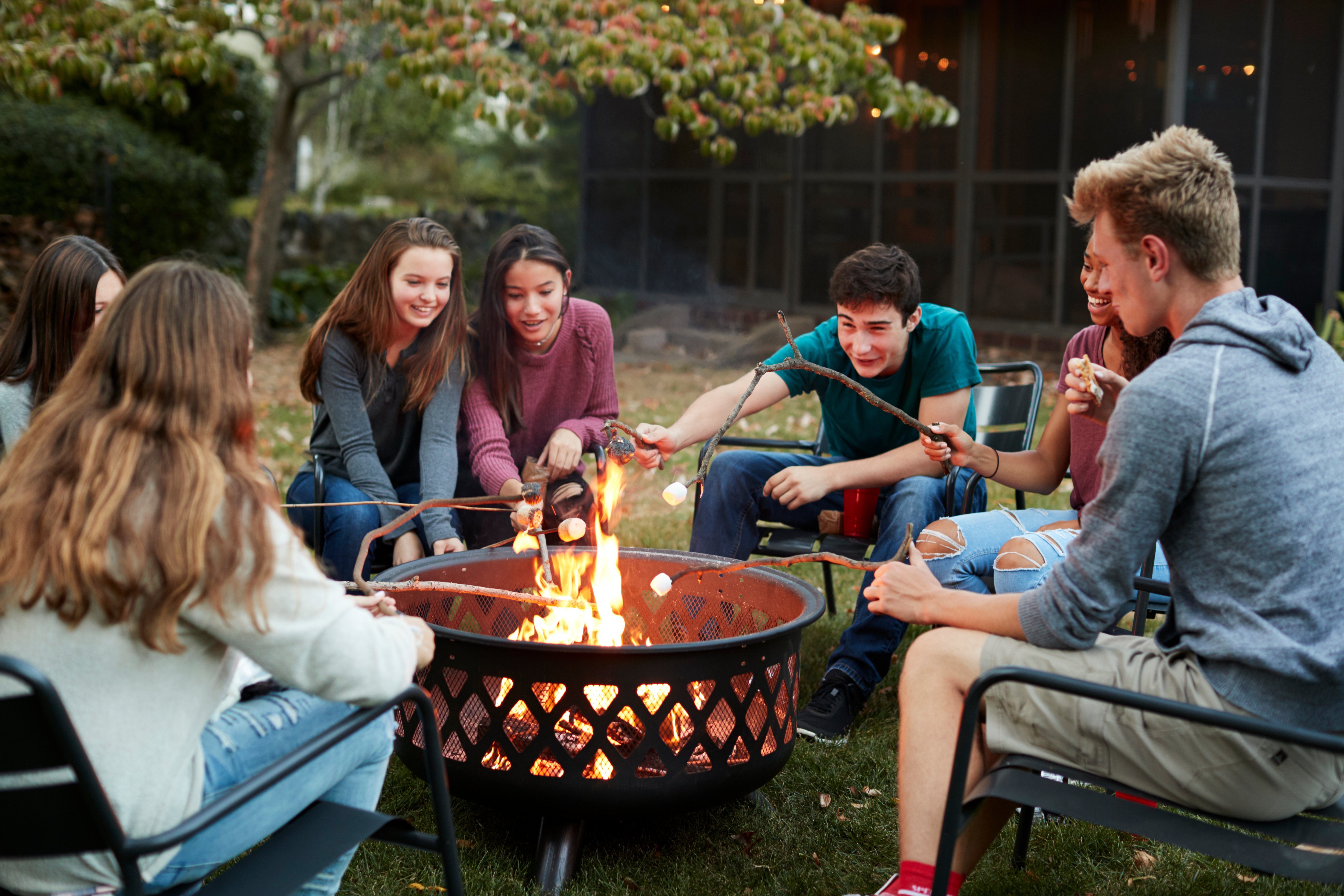 Teenagers roasting marshmallows around a fire