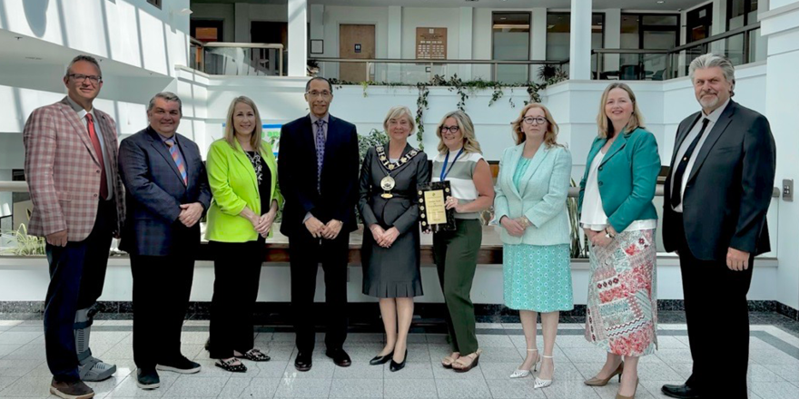 Mayor and Council posing with members of the Finance department holding the award