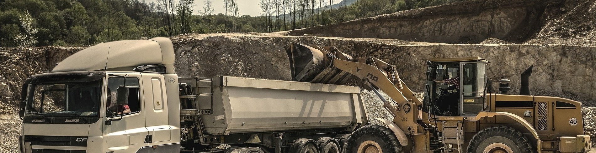 Yellow loader unloading stone into truck