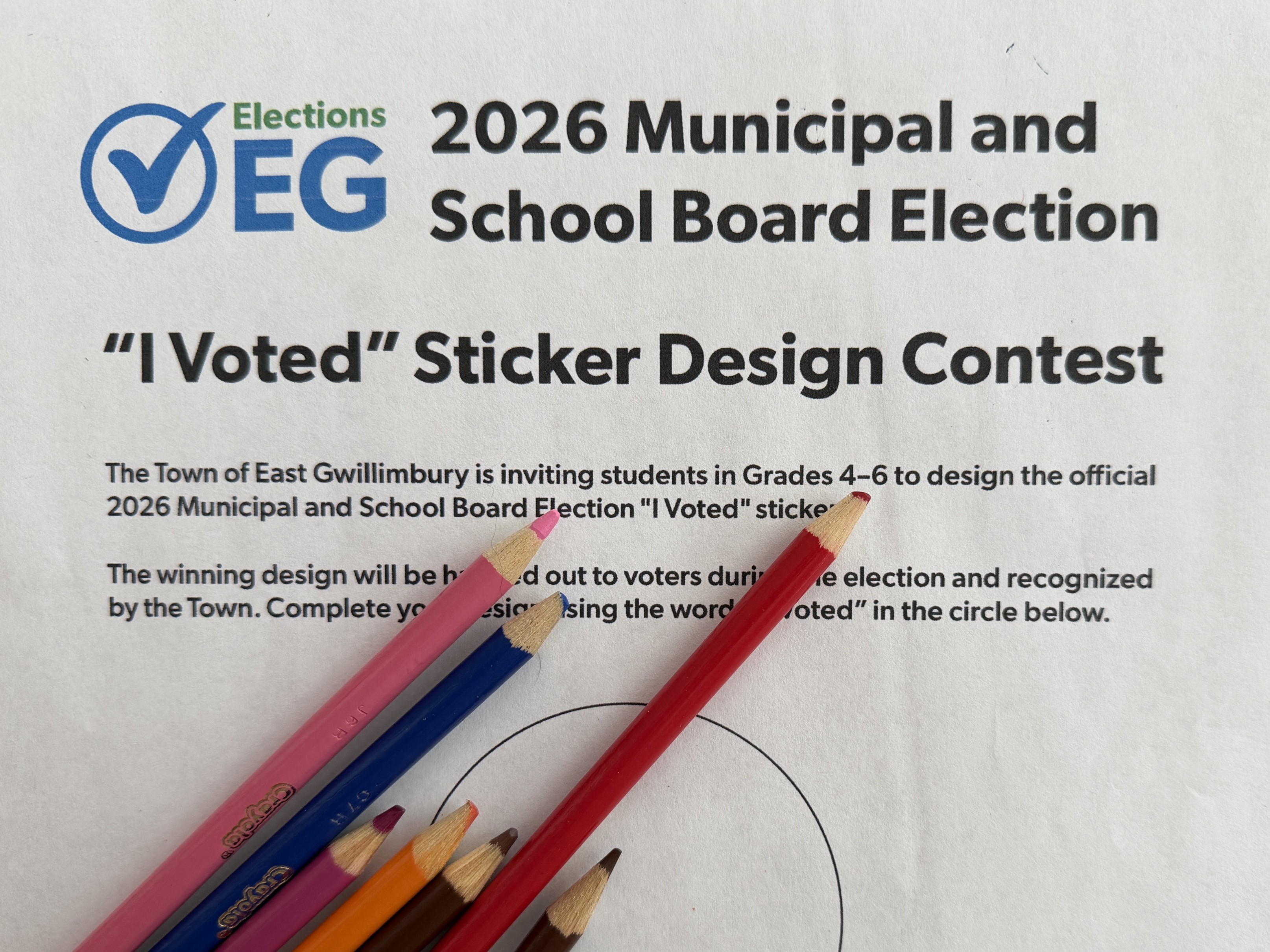 Promotional poster for the Town of East Gwillimbury’s 2026 Municipal and School Board Election “I Voted” Sticker Design Contest. The poster invites students in Grades 4 to 6 to design the official “I Voted” sticker for the 2026 election. A blank circle for the sticker design appears in the centre of the page, partially covered by several coloured pencils in pink, blue, orange, purple, brown, red, and green. The submission deadline is October 1, 2026, at 11:59 p.m., with additional contest information available at ElectionsEG.ca.