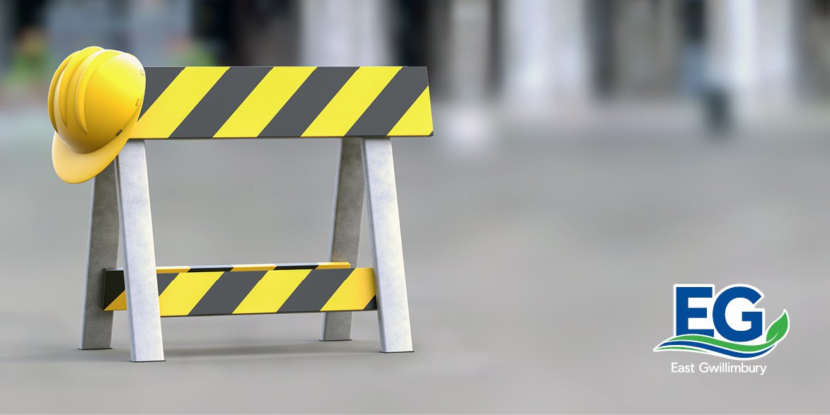 Black and yellow construction barricade with yellow hardhat hanging on corner