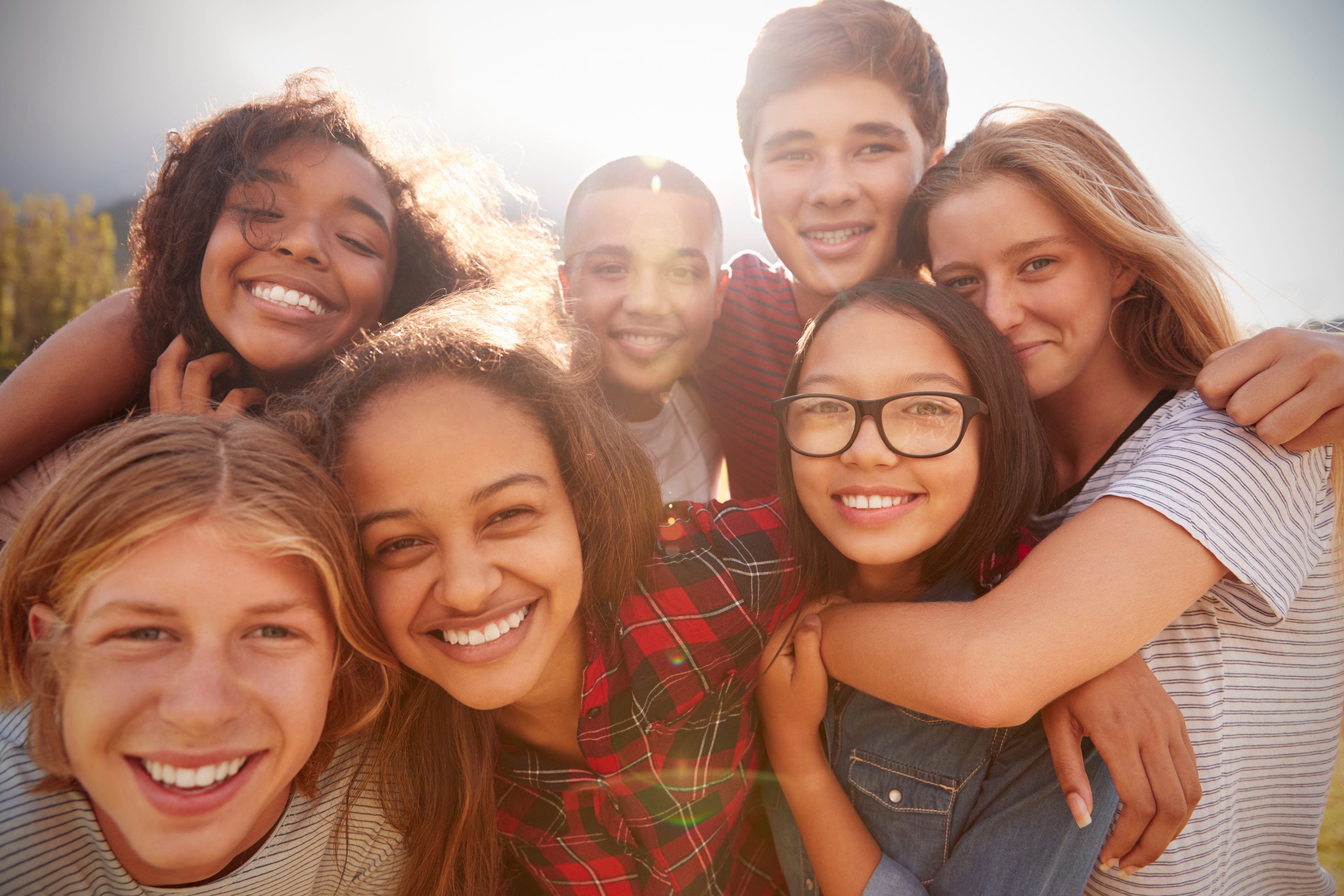 Smiling happy teens huddled together