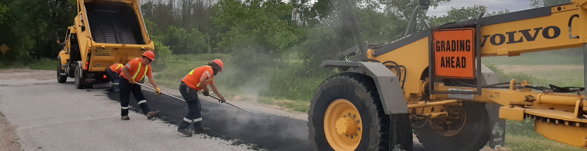 Team spreading new asphalt over road