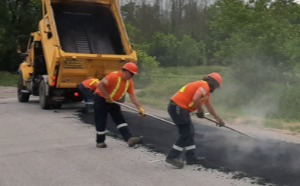 Team spreading new asphalt over road